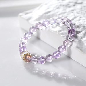 Pulsera de amatista natural de 8mm con dije de corona dorada sobre base de piedra