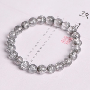 8mm natural silver rutile quartz beaded bracelet shown on a vintage calligraphy background