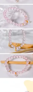 Detail of 8mm pink quartz beads bracelet featuring a white pearl charm and gold accents