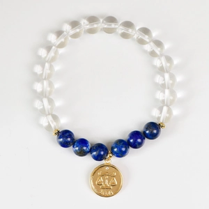 Natural crystal bead bracelet with Libra zodiac gold pendant on a white background