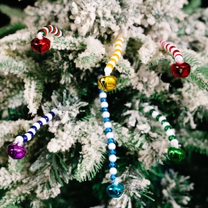 Detail van kleurrijke kerstkralen decoraties met bellen op een besneeuwde boomtak