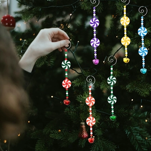 Dettaglio di perline colorate a forma di bastoncino e campanelli su albero di Natale