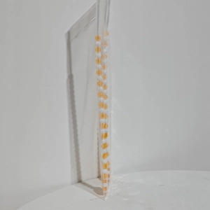 Detail van kerst zuurstok steker met gele en witte kralen in plastic verpakking