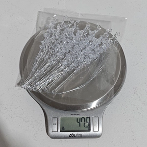 Detailed view of 12pcs clear acrylic icicle ornaments on a digital scale for weight check