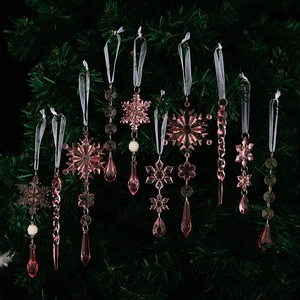 Pink acrylic snowflake and icicle ornaments hanging on a dark green Christmas tree branch