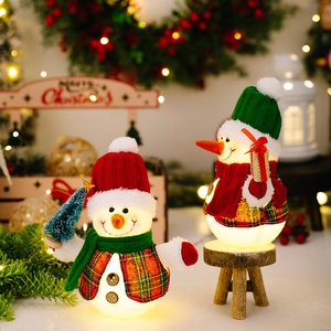 Macro detail of glowing plush snowmen figurines with plaid outfits and warm LED lighting