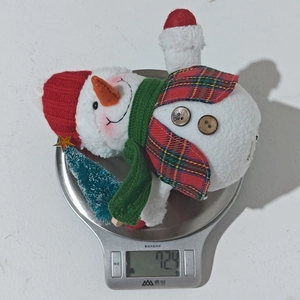Detailed view of lightweight 72g plush Christmas snowman ornament on an electronic scale