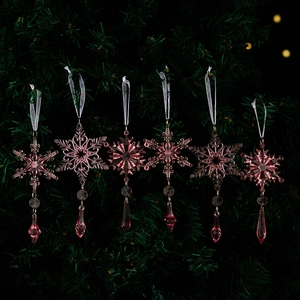 Detail of pink crystal snowflake ornaments with teardrop beads hanging on a Christmas tree