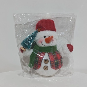Close-up of glowing Christmas snowman plush toy with knitted hat and miniature tree