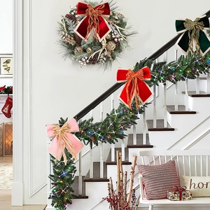 Detail of red and green velvet Christmas bows with gold edges on white staircase garland