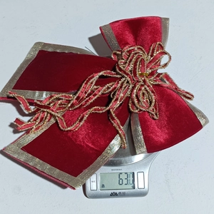 Détail macro d'un grand nœud de Noël en velours rouge avec bordure dorée de 63g