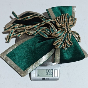 Detail shot of a dark green velvet bow on a scale showing a weight of 59.8g