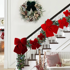 Close-up of premium red and green velvet bows decorating staircase greenery for Christmas