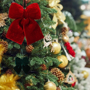 Close-up of premium red and dark green velvet Christmas bows hanging on a festive tree