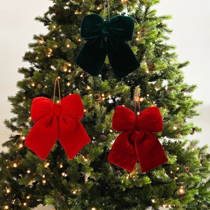 Close-up of premium red and green velvet Christmas bows hanging on a festive tree