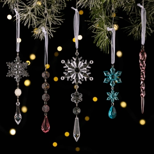 Christmas acrylic snowflake and ball ornaments in assorted colors on snowy pine branches