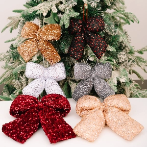 Glitter Christmas bow ornaments in six colors hanging on a snow-decorated tree