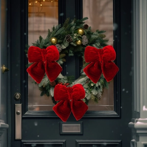 Three red velvet Christmas bows hanging on a festive green wreath against a black door