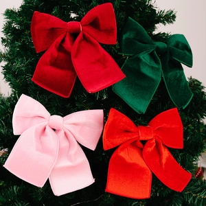Macro shot of red and green velvet Christmas bows hanging on a green tree branch
