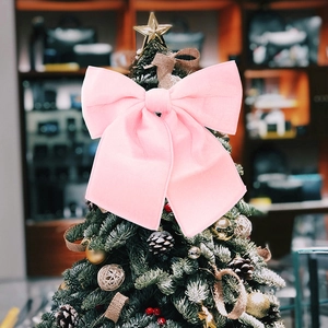 Close-up of a large pink velvet Christmas bow decoration hanging on a festive tree
