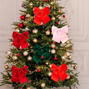 Detail of red gold velvet Christmas tree bows hanging on a decorated festive tree branch