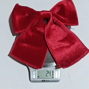 Macro shot showing the 24.1g weight of the red velvet Christmas bow on a digital scale