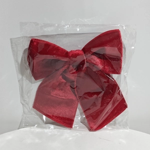 Large red velvet Christmas bow decoration in clear plastic packaging for holiday tree