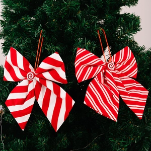 Detail of red and white striped Christmas bows with candy button on green pine tree