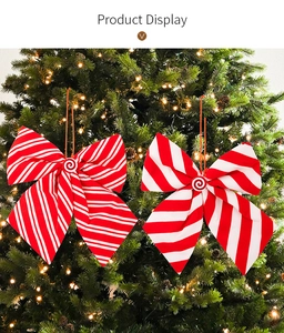 Detail of red and white striped Christmas bows with candy centers on a lighted tree