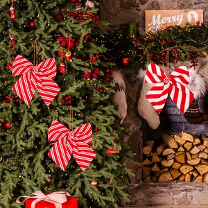 Close-up of red and white striped Christmas bows with lollipop center on a pine tree
