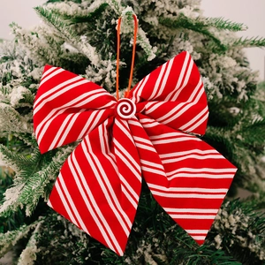 Close-up of red and white striped bow ornament with candy center on snowy Christmas tree