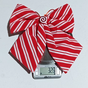 Detail of red and white striped Christmas bow with candy center on a digital scale