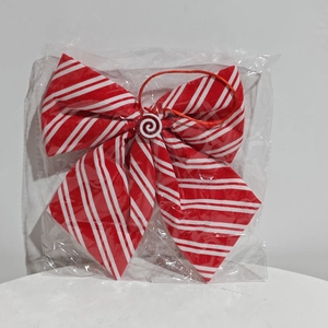 Detail view of a red and white striped Christmas bow ornament in clear protective packaging