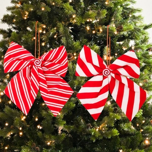 Red and white striped Christmas bow ornaments with candy center on a festive tree