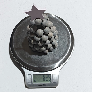 Mesure du poids d'un sapin de Noël en perles de bois grises avec étoile rose