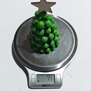 Détail d'un sapin de Noël en perles de bois vertes pesé sur une balance numérique