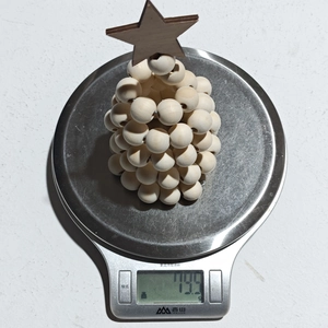 Vue détaillée montrant le poids de 79,3g du sapin de Noël en perles de bois sur balance
