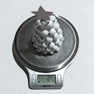 Détail d'un sapin de Noël en perles blanches sur une balance pesant 84,3 grammes