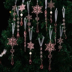 Pink acrylic Christmas ornaments with snowflake and icicle designs on a green tree