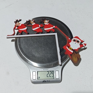 Detail shot showing a 22.9g Christmas reindeer and Santa door frame wood ornament on a scale