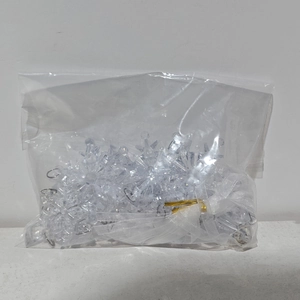 Clear acrylic snowflake ornaments set with white ribbons in packaging for Christmas decor