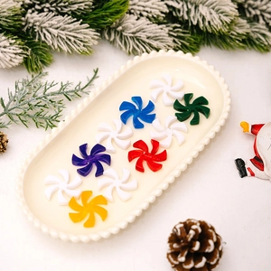 Colorful peppermint swirl ornaments on a white plate with Christmas decor details