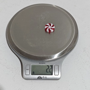 Detail showing the 2.2g weight measurement of a red and white spiral candy ornament