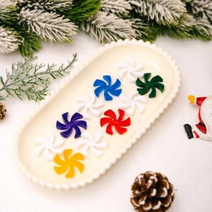 Colorful windmill Christmas ornaments in a ceramic tray with festive pine cone decor