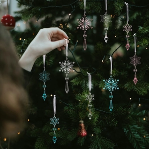 Detailed view of clear, pink and blue crystal snowflake pendants on a green Christmas tree