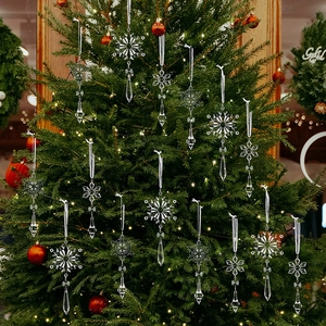 Macro shot of clear acrylic snowflake and teardrop ornaments hanging on a Christmas tree