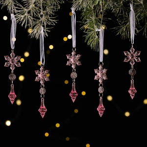 Close-up of pink crystal snowflakes and teardrop pendants hanging on Christmas branches