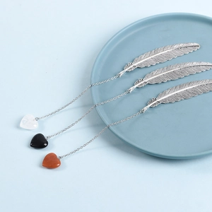 Silver feather bookmark with heart-shaped crystal charms in black, white, and red brown