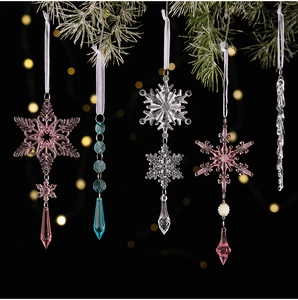 Detail von Acryl-Weihnachtsflocken und Eiszapfen-Anhängern an grünen Tannenzweigen