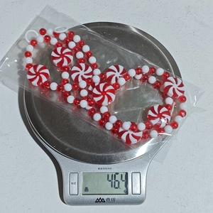 Detailed view of red and white peppermint candy beads on a scale for Christmas DIY decor